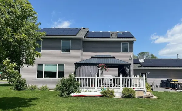 Two-story home with dark gray architectural shingle roof and rooftop solar panels